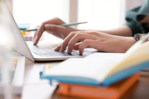 The image shows a man taking an online exam on a laptop.