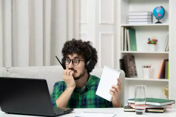 The image shows an anxious man trying to cheat by copying however he was detected by the teacher